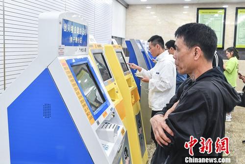 People check their information on a machine in Exit-Entry Administration Division of Guangzhou Public Security Bureau. (File photo/China News Service)