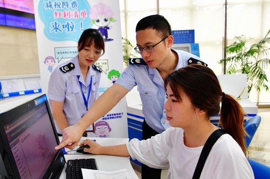 Staff members of tax service help a financial staff of a company (R) to print out a list of her company's tax cuts and fee reductions in Fuzhou, capital of southeast China's Fujian Province, Aug. 21, 2019. (Xinhua/Wei Peiquan)