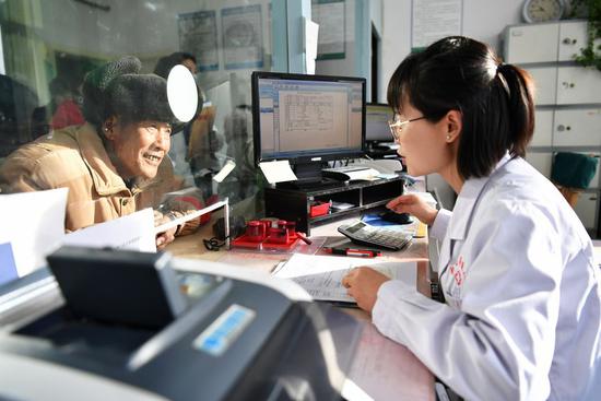 A staff member helps a patient with his check-out procedure in a hospital in Dunhuang, northwest China's Gansu Province, Dec. 19, 2019. (Xinhua/Chen Bin)