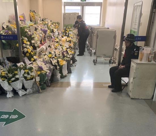 Staff members of the Civil Aviation General Hospital arrange flowers sent by grieving citizens in Beijing on Sunday. On Tuesday, Yang Wen, a doctor working in the emergency department at Civil Aviation General Hospital in Beijing, was stabbed by Sun Wenbin, a patient's relative. She died early the next day from serious neck injuries. (Photo by Wu Xiaohui/China Daily)