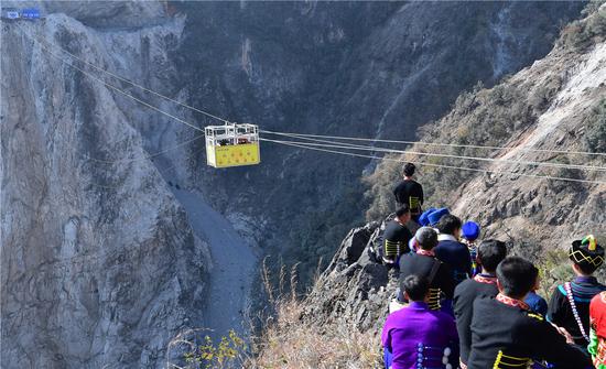 Villagers dressed in Yi ethnic clothes wait for a cable car to reach their far-flung village of Abuluoha in Butuo county, Sichuan province, on Tuesday, when the cableway was put into operation.  (Photo: For China Daily/He Haiyang)