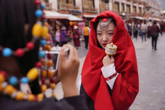 A tourist poses on Barkhor Street, a circular road with numerous shops, which winds around Jokhang Monastery in Lhasa, Tibet autonomous region last summer. (Photo: Xinhua Sun Fei)