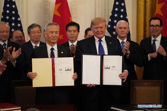 U.S. President Donald Trump and Chinese Vice Premier Liu He, who is also a member of the Political Bureau of the Communist Party of China Central Committee and chief of the Chinese side of the China-U.S. comprehensive economic dialogue, show the signed China-U.S. phase-one economic and trade agreement during a ceremony at the East Room of the White House in Washington D.C., the United States, Jan. 15, 2020. (Xinhua/Wang Ying)