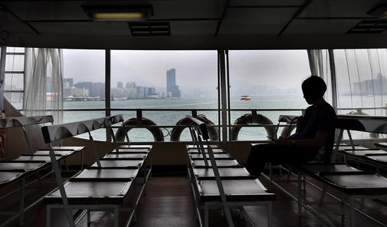 A passenger takes a ferry from Wan Chai ferry pier to Tsim Sha Tsui in Hong Kong in October. Ongoing violence has affected tourism, finance, retail, and other sectors. (Photo/Xinhua)