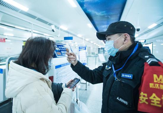A security staff checks a passenger's body temperature on the subway in Wuhan, central China's Hubei Province, Jan. 23, 2020. (Xinhua/Xiao Yijiu)