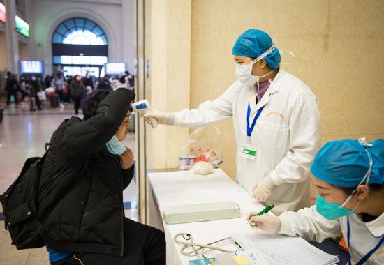 A medical worker takes a passenger's body temperature at Hankou Railway Station in Wuhan, capital of central China's Hubei Province, Jan. 22, 2020. (Xinhua/Xiao Yijiu)