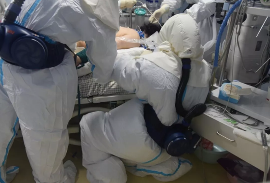 A nurse at Renmin Hospital of Wuhan's Donghu Districtat kneels on the ground to treat the patient in Wuhan, central China's Hubei Province. /Hubei Daily