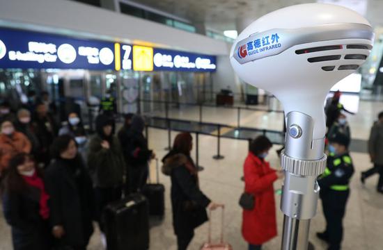 Security staffs check passengers' body temperature at the airport in Wuhan, central China's Hubei Province, Jan. 21, 2020. (Xinhua/Xiao Yijiu)