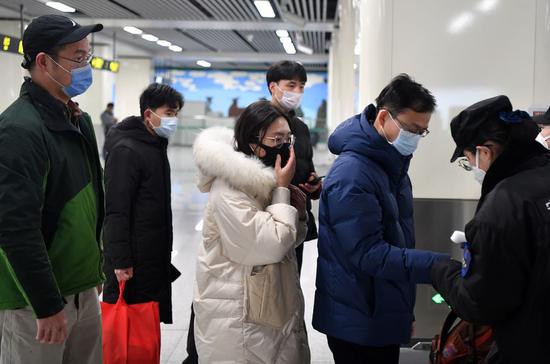 Passengers line up to have body temperatures measured at a station in Zhengzhou, central China's Henan Province, Jan. 26, 2020. (Xinhua/Li Jianan)