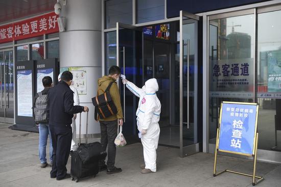 A staff member checks a passenger's body temperature at the entrance of the Wanzhou North Railway Station, Southwest China's Chongqing municipality, Feb 1, 2020. (Photo/Xinhua)