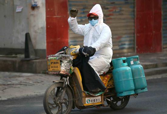 A worker, covering himself with a mask, glasses and a protective suit, delivers gas in the Jiang'an district of Wuhan, capital of Central China's Hubei province, on Feb 1. (Photo by Zhou Guoqiang/for chinadaily.com.cn)