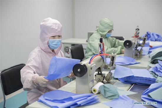 Workers make protective suits to help combat novel coronavirus