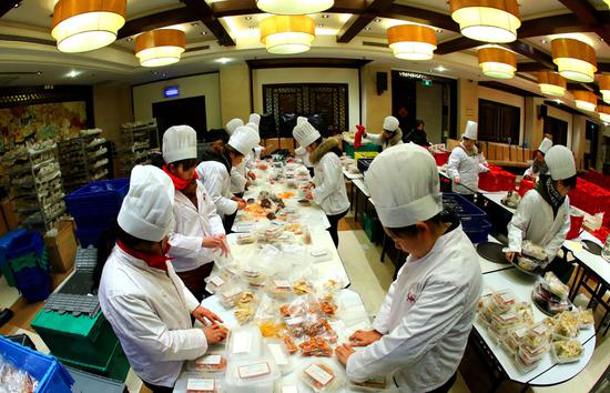  Restaurant employees prepare takeaway Lunar New Year's Eve dinner dishes at Deyuelou Restaurant in Suzhou, East China's Jiangsu province. (Photo by Wang Jianzhong/For China Daily)