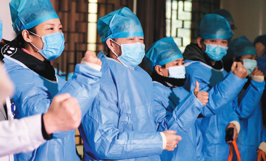 Patients who have recovered from the novel coronavirus gesture to show their determination in the struggle against the outbreak at Hubei Provincial Hospital of Integrated Chinese and Western Medicine in Wuhan on Thursday. Traditional Chinese medicine played a key role in their recovery.  (Photo/China Daily)