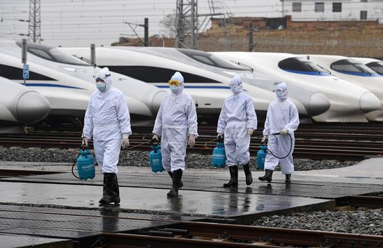 Staff members of China Railway Nanning Group Co., Ltd. walk out of bullet trains after disinfection work in Nanning, south China's Guangxi Zhuang Autonomous Region, Feb. 6, 2020. (Xinhua/Lu Boan)