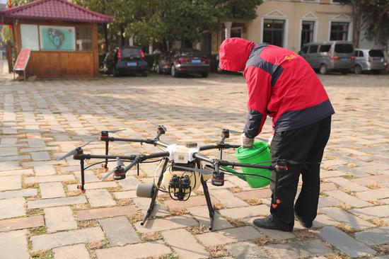 A worker loads disinfectant into containers on a drone in Kunming, capital of southwest China's Yunnan Province on Feb.8, 2020. (Xinhua/Wang Anhaowei)