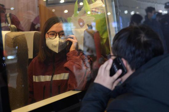 A medical team member (L) of the Second Xiangya Hospital of Central South University says goodbye to her family member via mobile phone at Changsha South Railway Station in Changsha, central China's Hunan Province, Feb. 8, 2020. (Xinhua/Chen Zhenhai)