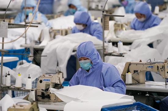Workers make protective suits for general purposes at a production line of Hodo Group, a private-owned garment company in Wuxi, east China's Jiangsu Province, Feb. 8, 2020. (Xinhua/Li Bo)