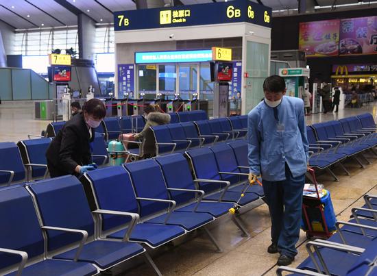 Workers disinfect a waiting room at Beijing South Railway Station on Thursday. REN CHAO / XINHUA