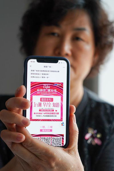 A resident displays an advertisement of an online shopping WeChat group published by a shopping mall in Nanjing, east China's Jiangsu Province, Feb. 15, 2020. (Xinhua/Li Bo)