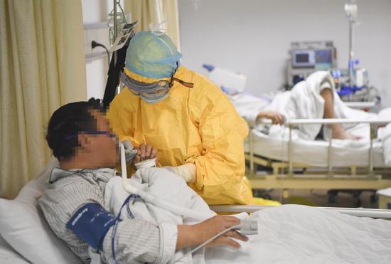 A medical worker helps a patient drink water at an isolation ward at a hospital in southwest China's Chongqing, Feb. 1, 2020. (Xinhua/Wang Quanchao)
