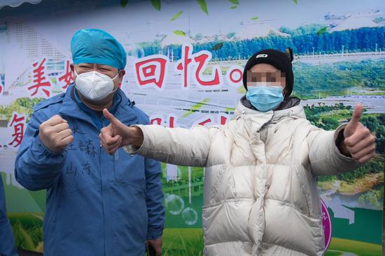 A recovered patient (R) infected with novel coronavirus pneumonia (NCP) expresses gratitude to medical staff with a gesture to cheer Wuhan up at a temporary hospital converted from Wuhan International Expo Center in Wuhan, central China's Hubei Province, Feb. 21, 2020. (Xinhua/Xiao Yijiu)
