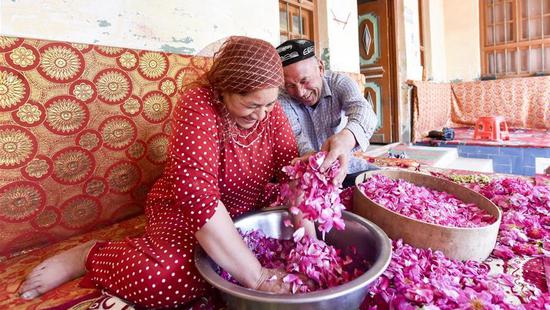 Flower grower Ruz and his wife Tajinisa make rose sauce at a village in Hotan, Northwest China's Xinjiang Uygur autonomous region, June 6, 2018. (Photo/Xinhua)