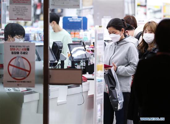Local residents wait to pay at the counter in a shop in Seoul, South Korea, Feb. 24, 2020. South Korea confirmed 231 more cases of the COVID-19 on Monday, raising the total number of infections to 833, and the death toll rose to eight. The country raised its four-tier virus alert to the highest 