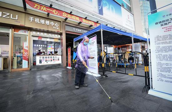 A staff member disinfects the ground at Huaqiangbei commercial area in Shenzhen, south China's Guangdong Province, Feb. 24, 2020. Huaqiangbei, a renowned commercial area in Shenzhen for electronics markets, has set up some 100 tents outdoor for commercial tenants to help them resume businesses with epidemic prevention and control measures. (Xinhua/Mao Siqian)