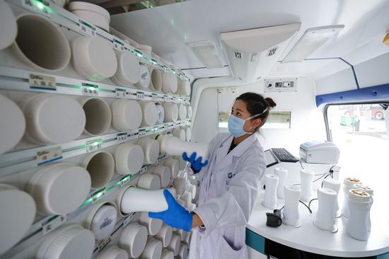 Medical worker Wu Zhiting takes boxes of concentrate granules from a shelf at the mobile emergency smart pharmacy for traditional Chinese medicine (TCM) at a temporary hospital in Jiangxia District in Wuhan, central China's Hubei Province, Feb. 26, 2020. (Xinhua/Shen Bohan)