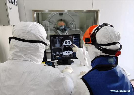 Photo taken with a mobile phone on Feb. 23, 2020 shows medical workers checking a patient's CT image with a movable CT machine at the 
