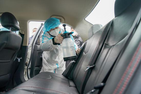 A staff member of DiDi Chuxing, a car-hailing service firm, disinfects a vehicle in Nanjing, east China's Jiangsu Province, Feb. 14, 2020. (Xinhua/Li Bo)