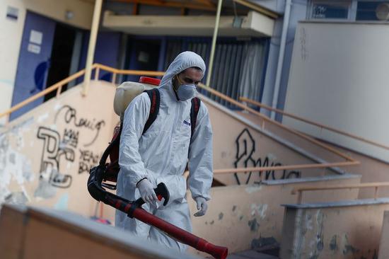 A man wearing a protective suit decontaminates a primary school where a child was diagnosed with coronavirus in Thessaloniki, Greece, Feb. 27, 2020.(Photo by Dimitris Tosidis/Xinhua)