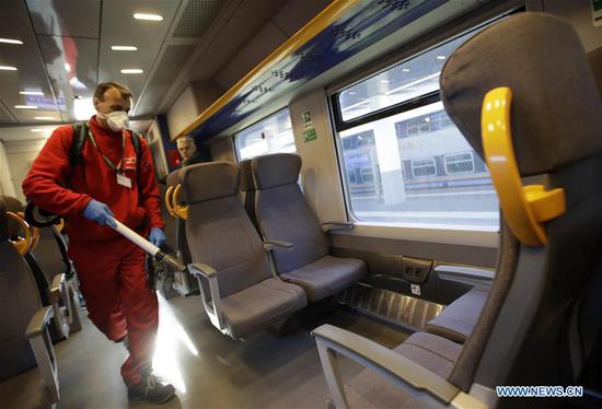 A staff member sanitizes the facilities on a train at the Garibaldi train station in Milan, Italy, Feb. 28, 2020.  (Photo by Alberto Lingria/Xinhua)