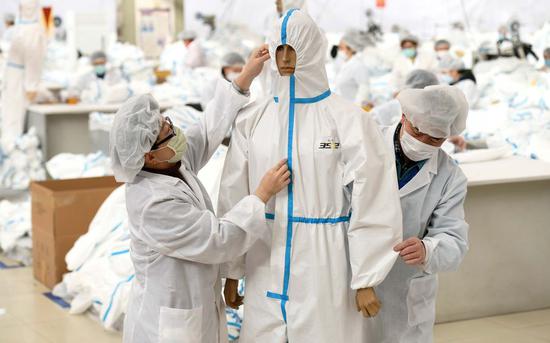 Workers make protective suits at a production line of a clothes company in Shijiazhuang City, north China's Hebei Province, Feb. 18, 2020. (Photo by Chen Qibao/Xinhua)
