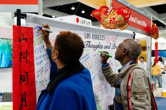 Visitors write down words in support of China's fight against the novel coronavirus at the annual Los Angeles Travel & Adventure Show in Los Angeles, the United States, Feb. 15, 2020. (Xinhua/Qian Weizhong)
