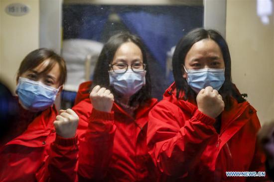 Medical team members cheer up for themselves before leaving for Hubei Province at Chongqing North Railway Station in southwest China's Chongqing on Feb. 28, 2020.  (Photo by Huang Wei/Xinhua)