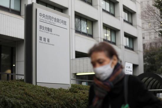 A pedestrian wearing a face mask passes by the office building of the Ministry of Health, Labour and Welfare in Tokyo, Japan, Feb. 25, 2020. (Xinhua/Du Xiaoyi)