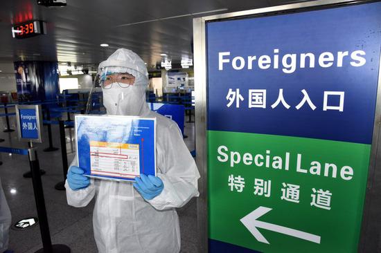 A staff member reminds foreigners to fill in an arrival card at Qingdao Liuting International Airport in Qingdao, east China's Shandong Province, March 5, 2020. (Xinhua/Li Ziheng)