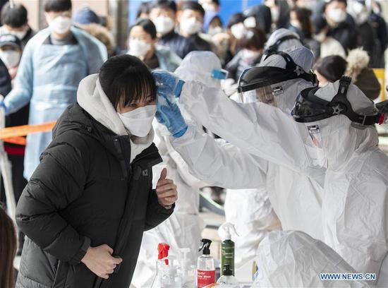 A medical worker collects samples of a tested citizen at Guro-gu district of Seoul, South Korea, March 10, 2020. (Photo by Lee Sang-ho/Xinhua)