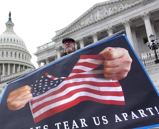 A protester holding a poster stands in front of the Capitol in Washington D.C., the United States, Feb. 3, 2020. (Xinhua/Liu Jie)