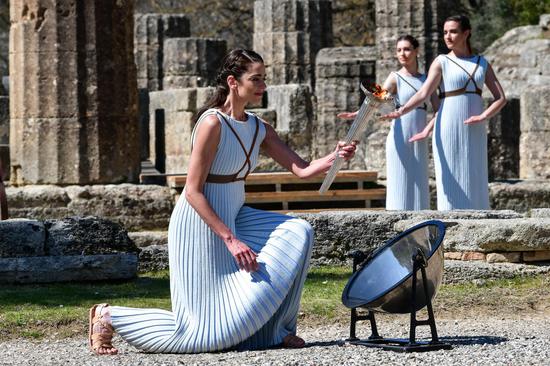 The lead performer in the ceremony styled as the 'High Priestess of the Goddess Hera', is seen with the Olypmic Flame during the lighting ceremony in Ancient Olympia, Greece, on March 12, 2020. The Olympic Flame which will be burning for the Tokyo 2020 Olympics was ignited in Ancient Olympia in western Greece, the birthplace of the Games, on March 12, 2020. (Xinhua/Antonis Nikolopoulos)
