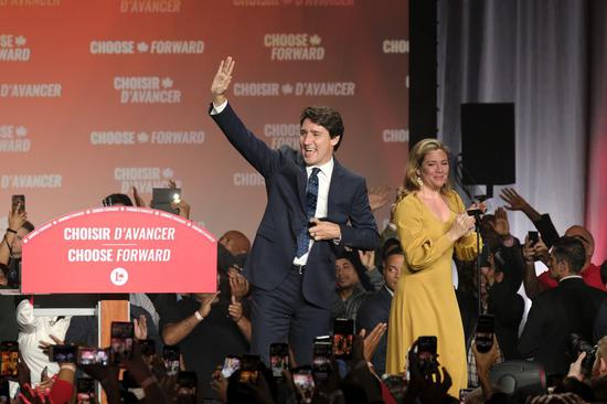Canadian Prime Minister Justin Trudeau (L) and his wife Sophie Gregoire Trudeau wave to people at the Liberal Party campaign headquarters in Montreal, Canada, Oct. 21, 2019. (Photo by Raffi Kirdi/Xinhua)