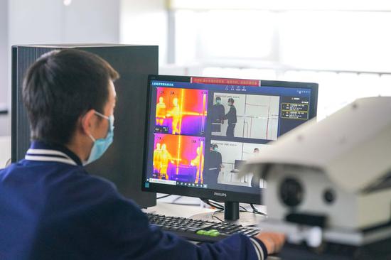 A technician of the Harbin Xinguang Optic-Electronics Technology Co., Ltd. adjusts the spectrum thermometer in Harbin, northeast China's Heilongjiang Province, March 13, 2020. (Xinhua/Wang Song)