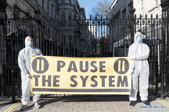 Activists stage a protest outside 10 Downing Street against the British government's handling of the COVID-19 outbreak in London, Britain on March 16, 2020. British scientists have urged the government to take 
