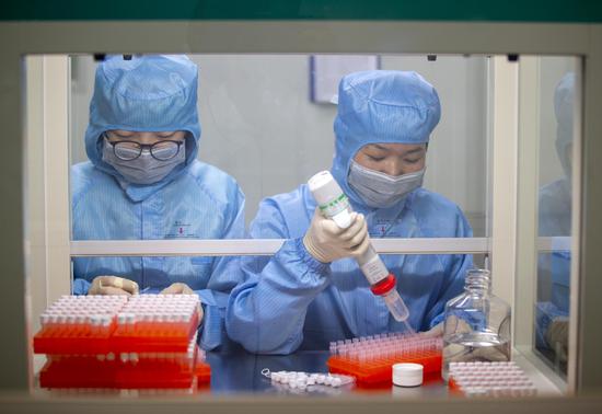 Employees check novel coronavirus testing kits at the production facility of a biotech company in Taizhou, Jiangsu province. (Photo by Tang Dehong/For China Daily)