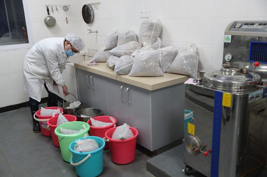 A doctor soaks packs of traditional Chinese medicine before boiling them at the Sixth Hospital of Wuhan in Hubei province on March 14, 2020. (Photo by Wang Jing/China Daily)