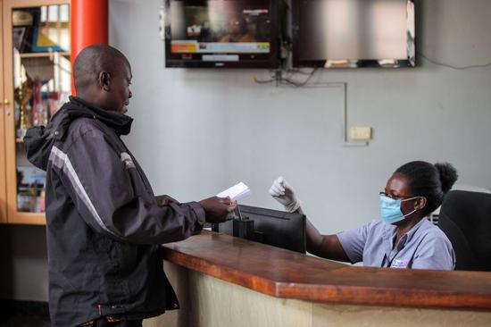 A receptionist wearing a face mask receives a client in Kampala, Uganda, March 18, 2020.(Xinhua/Hajarah Nalwadda)