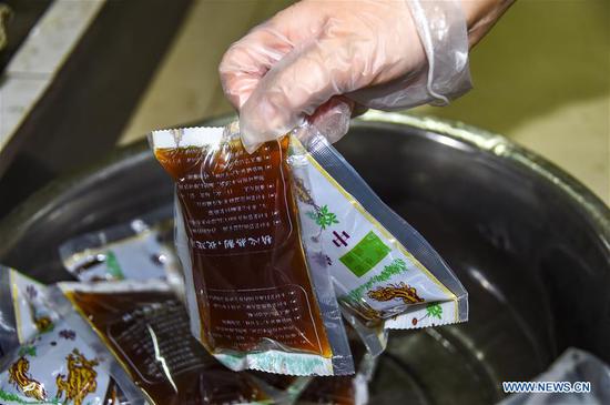A pharmacist of traditional Chinese medicine (TCM) arranges doses of TCM decoctions to help combat the novel coronavirus epidemic at Xiaogan Chinese Medical Hospital in Xiaogan city, central China's Hubei province, Feb 25, 2020. (Photo/Xinhua)