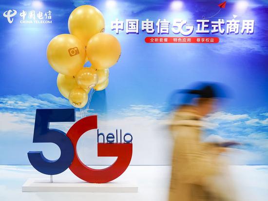 A consumer walks past a poster of commercial 5G applications outside a branch of China Telecom in Beijing, capital of China, Oct. 31, 2019. (Xinhua/Shen Bohan)